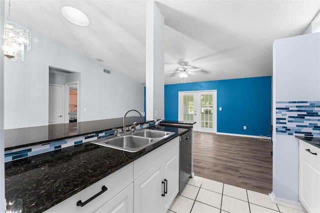 kitchen with dark stone countertops, french doors, light hardwood / wood-style flooring, sink, and pendant lighting