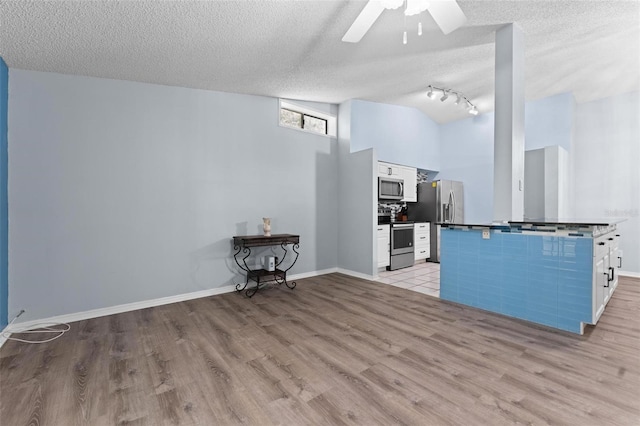 kitchen with light hardwood / wood-style flooring, appliances with stainless steel finishes, white cabinetry, ceiling fan, and a textured ceiling