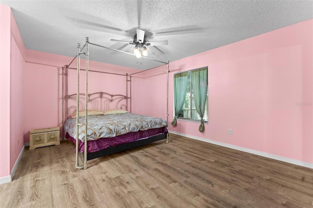 bedroom with a textured ceiling, hardwood / wood-style flooring, and ceiling fan