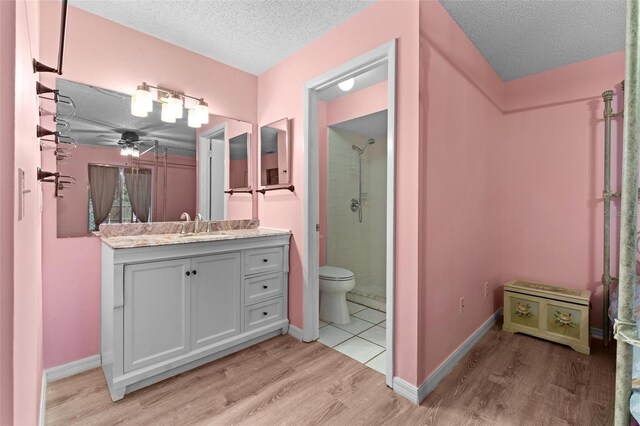 bathroom featuring hardwood / wood-style flooring, walk in shower, toilet, ceiling fan, and vanity