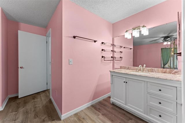 bathroom featuring vanity, a textured ceiling, hardwood / wood-style flooring, and ceiling fan