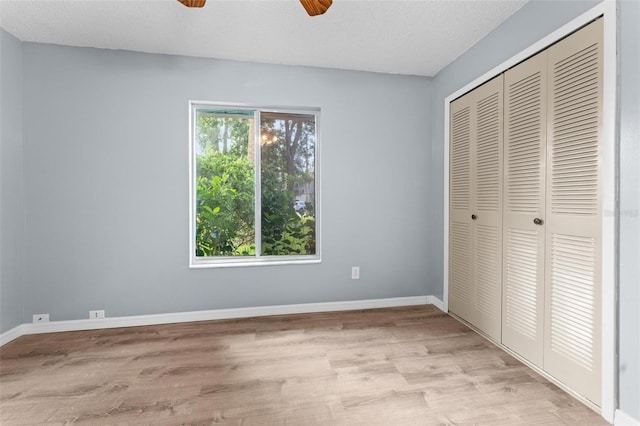 unfurnished bedroom featuring a textured ceiling, ceiling fan, a closet, and light hardwood / wood-style floors