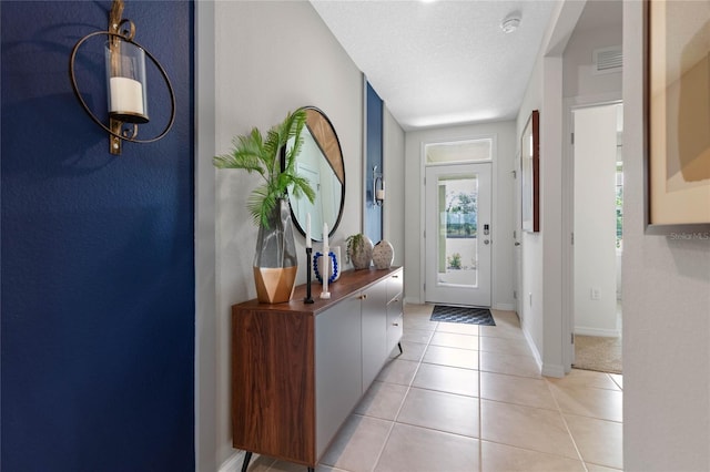 doorway featuring a textured ceiling and light tile patterned floors