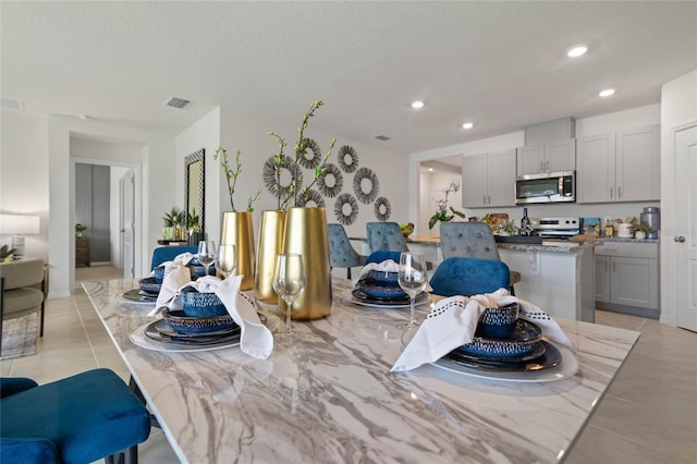 dining space featuring a textured ceiling and light tile patterned flooring