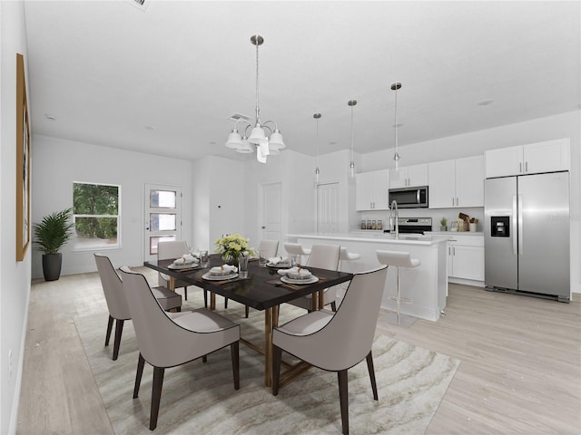 dining space featuring light wood-style flooring and an inviting chandelier