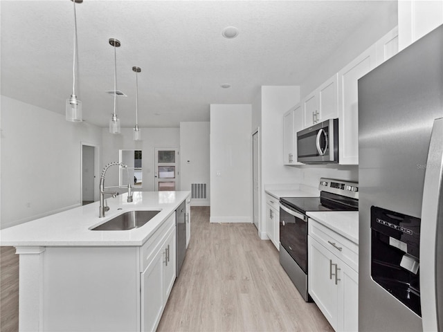 kitchen with light wood finished floors, light countertops, white cabinets, stainless steel appliances, and a sink