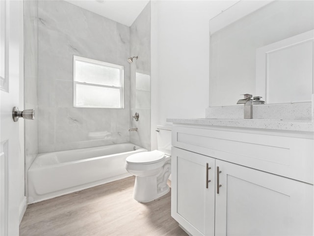 full bath with toilet, wood finished floors, vanity, and shower / tub combination