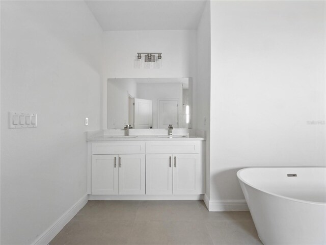 bathroom with a sink, a freestanding tub, baseboards, and double vanity