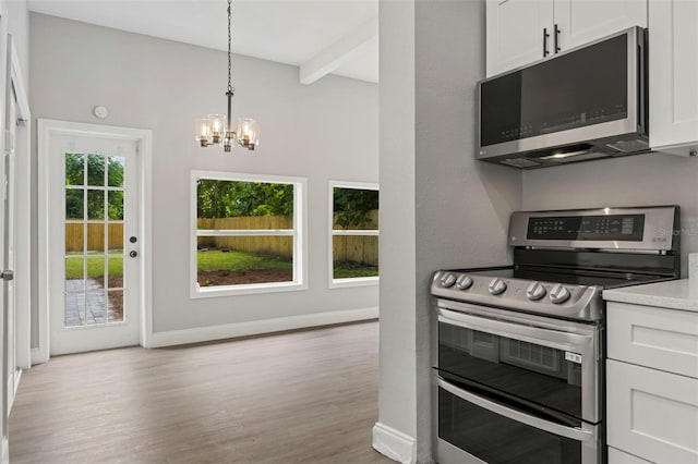 kitchen with white cabinets, appliances with stainless steel finishes, a chandelier, and light hardwood / wood-style flooring