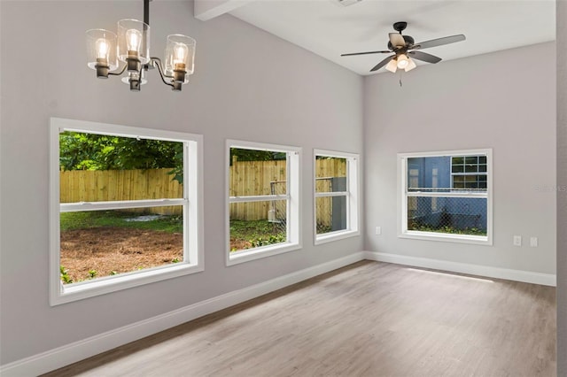 interior space with light hardwood / wood-style flooring, beamed ceiling, and ceiling fan with notable chandelier