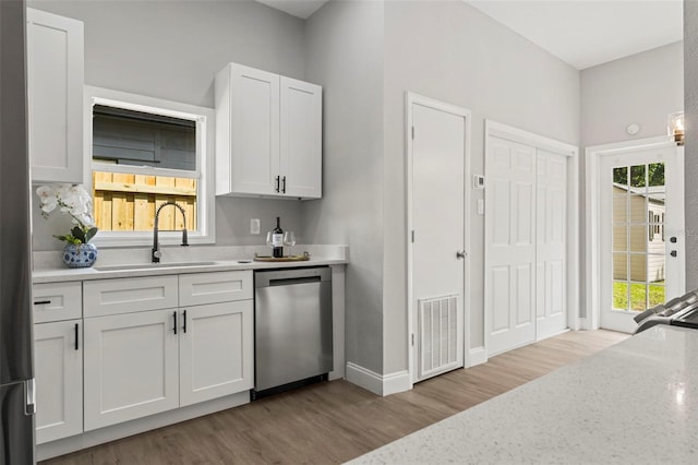 kitchen with dishwasher, white cabinetry, and plenty of natural light