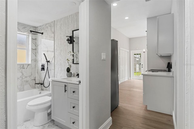 full bathroom featuring wood-type flooring, vanity, toilet, and tiled shower / bath