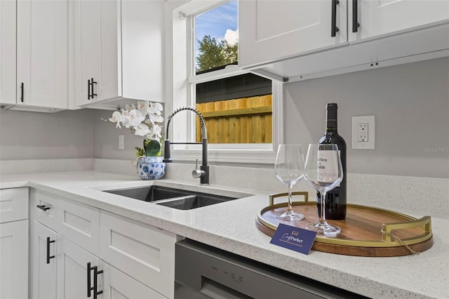 kitchen featuring light stone countertops, white cabinetry, and sink