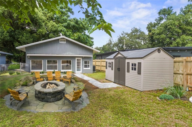 back of house featuring a storage shed, a yard, an outdoor fire pit, and a patio