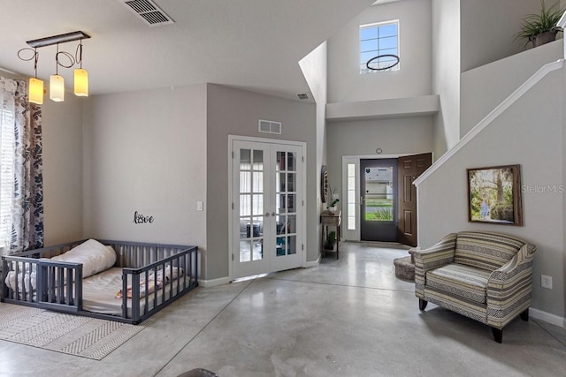 foyer with a high ceiling, a wealth of natural light, concrete floors, and french doors