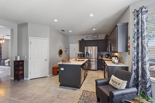 kitchen featuring a kitchen island with sink, stainless steel appliances, sink, and decorative backsplash