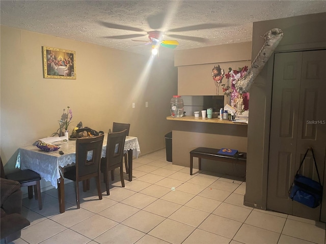 tiled dining area with a textured ceiling and ceiling fan