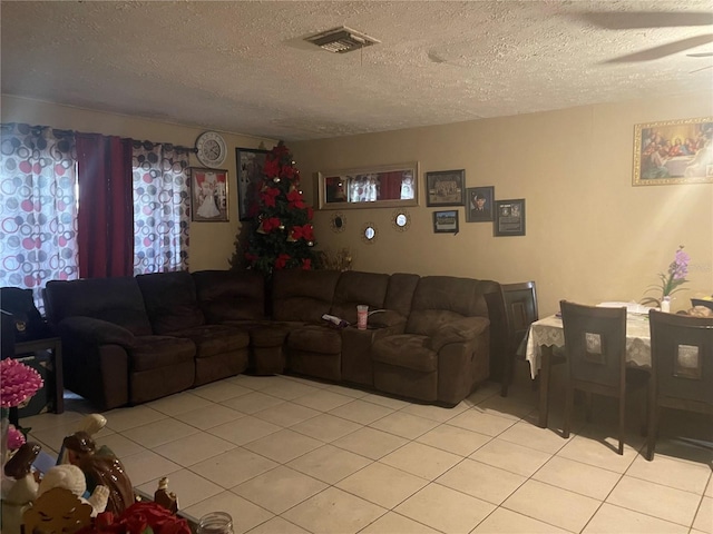 living room featuring ceiling fan, a textured ceiling, and light tile patterned floors