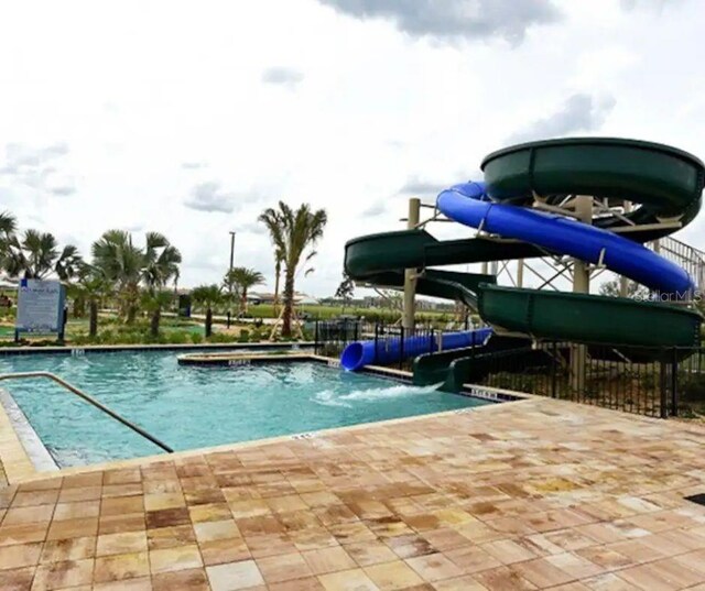 view of swimming pool with a water slide and a patio