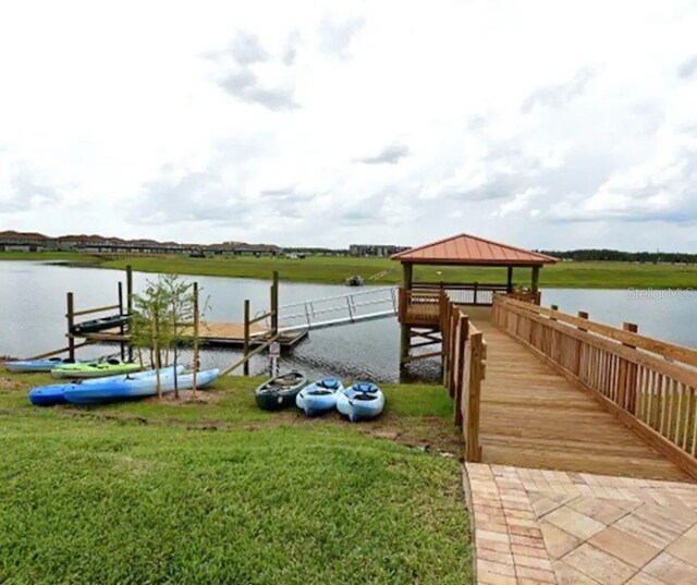 view of dock featuring a water view, a lawn, and a gazebo