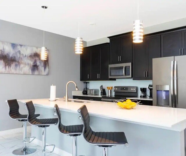 kitchen featuring appliances with stainless steel finishes, decorative light fixtures, sink, and a kitchen breakfast bar