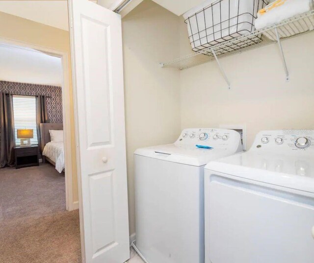 washroom with washing machine and dryer and light colored carpet