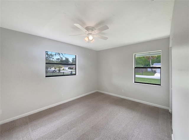 carpeted spare room featuring a wealth of natural light and ceiling fan