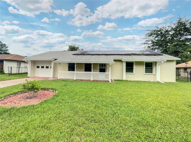 ranch-style home featuring covered porch, solar panels, a front yard, and a garage