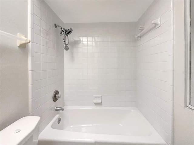 bathroom with toilet and tiled shower / bath