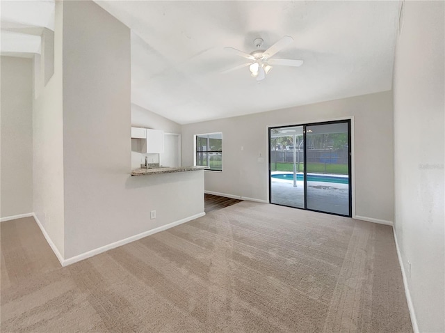 unfurnished living room featuring lofted ceiling, light colored carpet, and ceiling fan