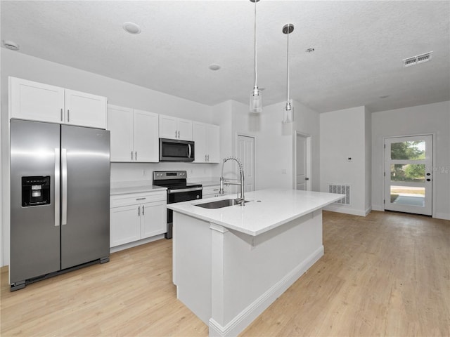 kitchen featuring hanging light fixtures, stainless steel appliances, white cabinetry, sink, and a kitchen island with sink