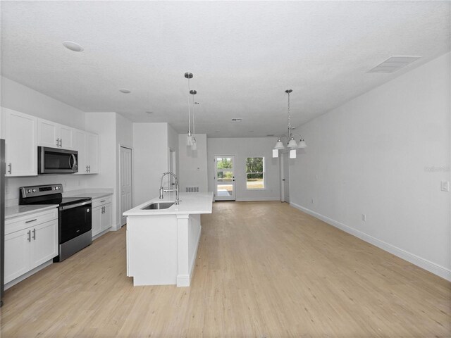 kitchen with light wood-type flooring, stainless steel appliances, white cabinetry, sink, and a center island with sink