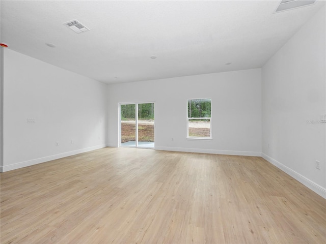 empty room featuring light wood-style floors, visible vents, and baseboards