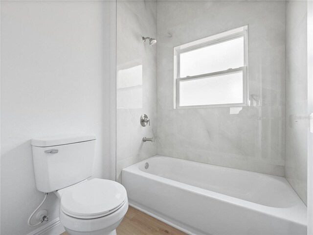 bathroom featuring toilet, wood finished floors, and bathing tub / shower combination