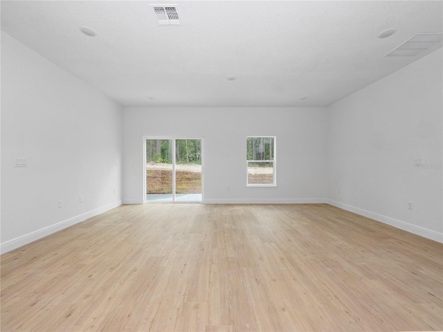 empty room featuring visible vents, baseboards, and light wood-style floors