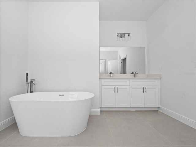 full bath featuring a sink, a freestanding bath, baseboards, and double vanity