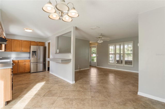 kitchen featuring stainless steel fridge, light tile patterned flooring, range hood, and ceiling fan with notable chandelier