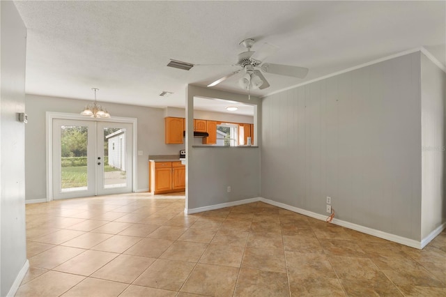 empty room featuring french doors, ceiling fan with notable chandelier, wooden walls, and light tile patterned floors