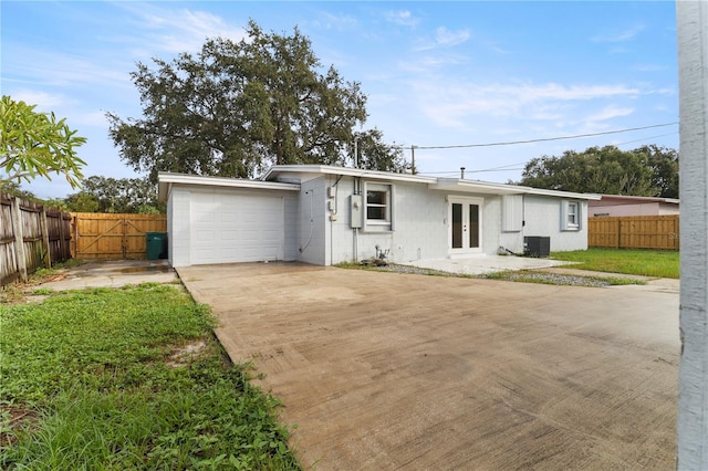 single story home with cooling unit and a garage