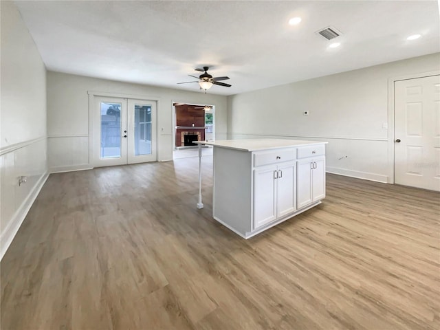 kitchen featuring visible vents, light wood-style floors, a brick fireplace, and open floor plan