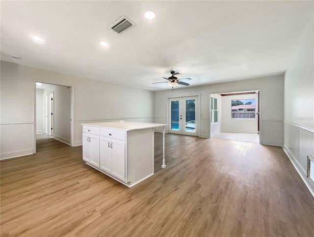 kitchen with visible vents, open floor plan, light wood-type flooring, french doors, and white cabinetry