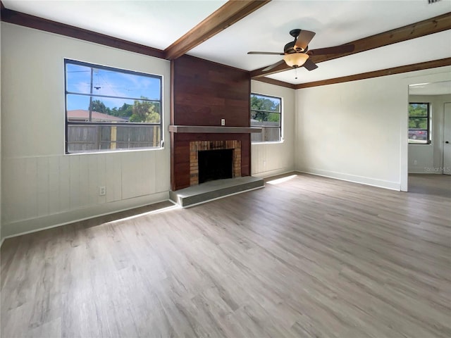 unfurnished living room featuring ceiling fan, beam ceiling, a brick fireplace, and hardwood / wood-style flooring