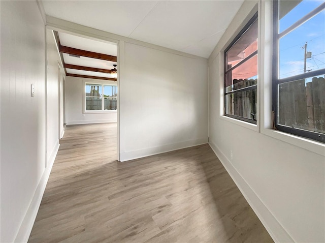 unfurnished room featuring beam ceiling, wood finished floors, baseboards, and ceiling fan