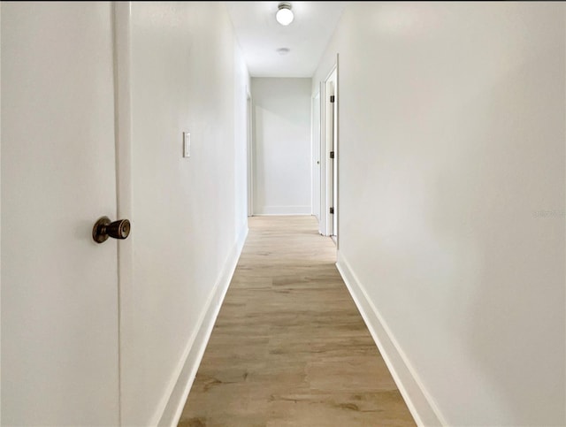 hallway with baseboards and light wood finished floors