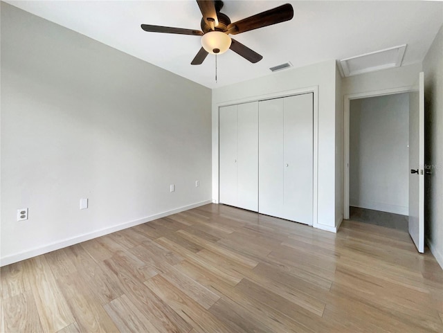 unfurnished bedroom with visible vents, baseboards, attic access, light wood-type flooring, and a closet