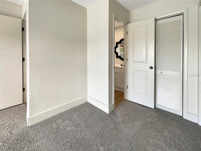 unfurnished bedroom with a closet, a sink, baseboards, and carpet floors