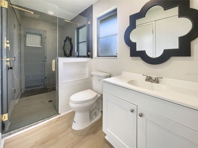 bathroom featuring a stall shower, toilet, vanity, and wood finished floors