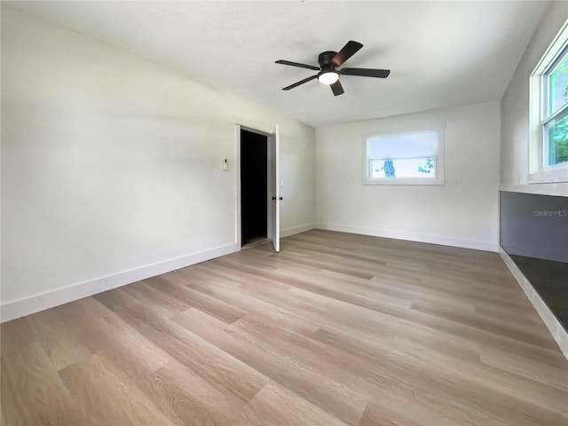 unfurnished room featuring a wealth of natural light, a ceiling fan, baseboards, and light wood finished floors