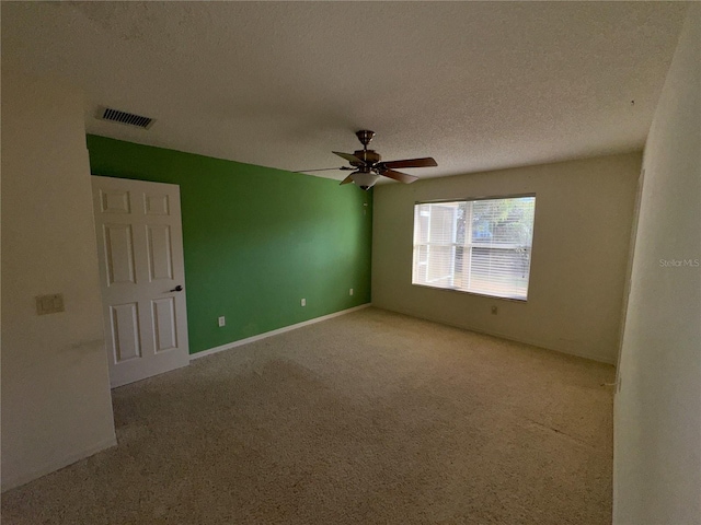 empty room with ceiling fan, carpet floors, and a textured ceiling