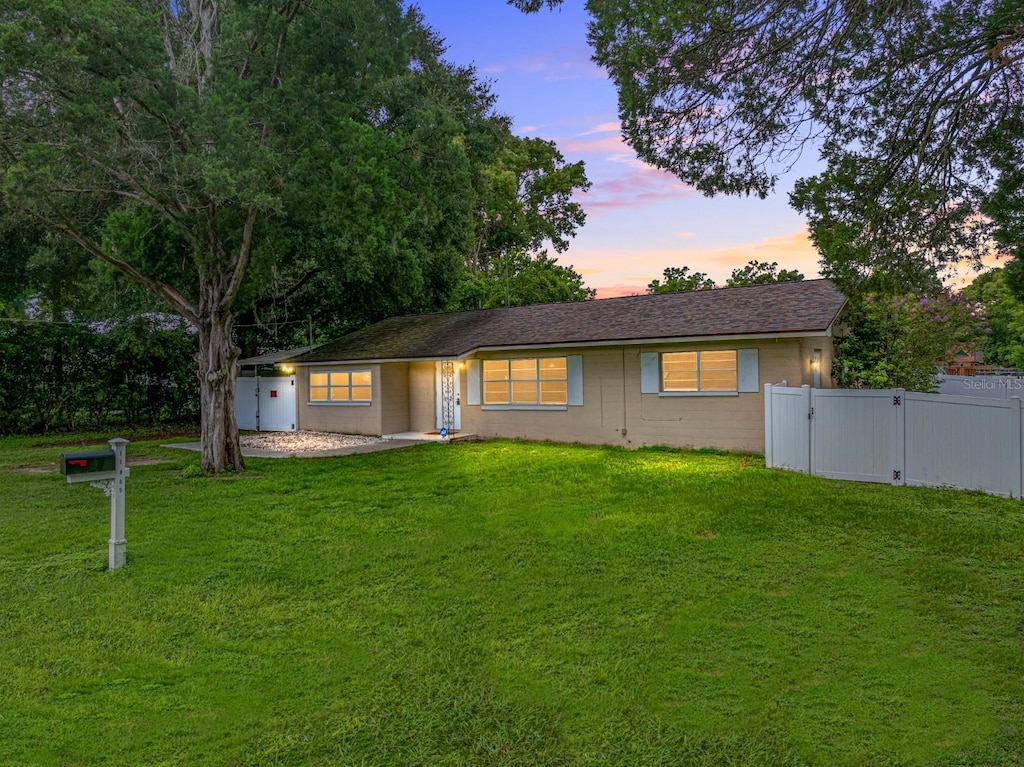 ranch-style home featuring a gate, a front yard, and fence